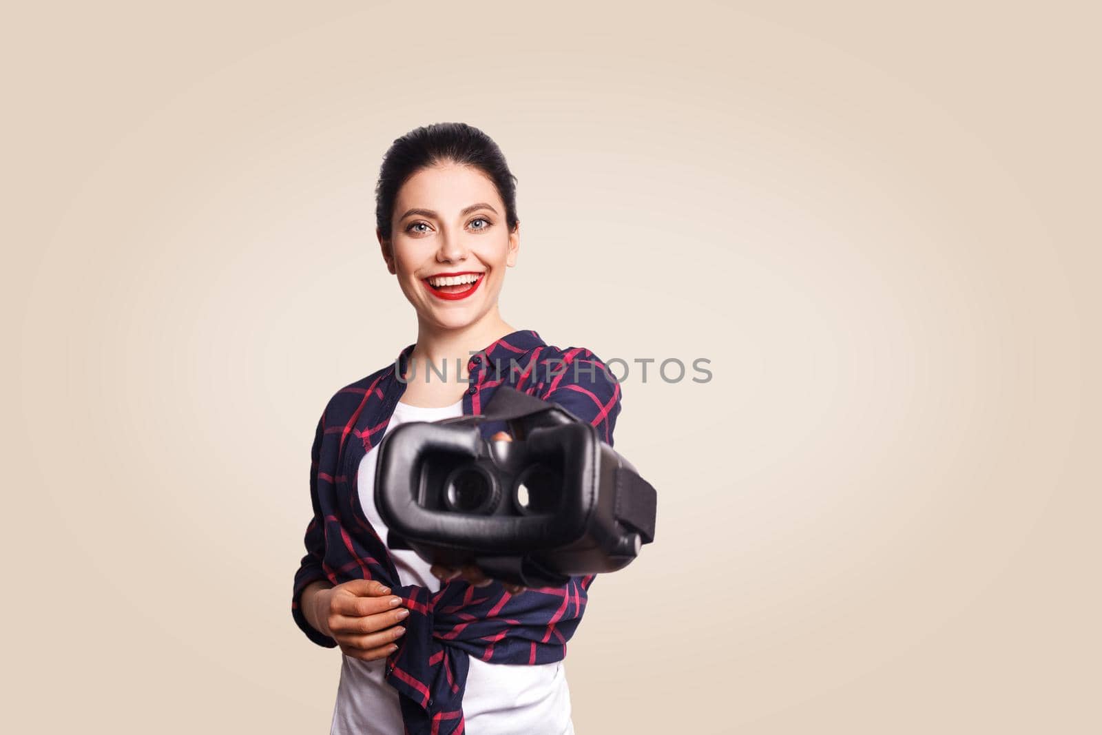 Young beautiful woman in casual style with virtual reality headset on beige background. studio shot. .