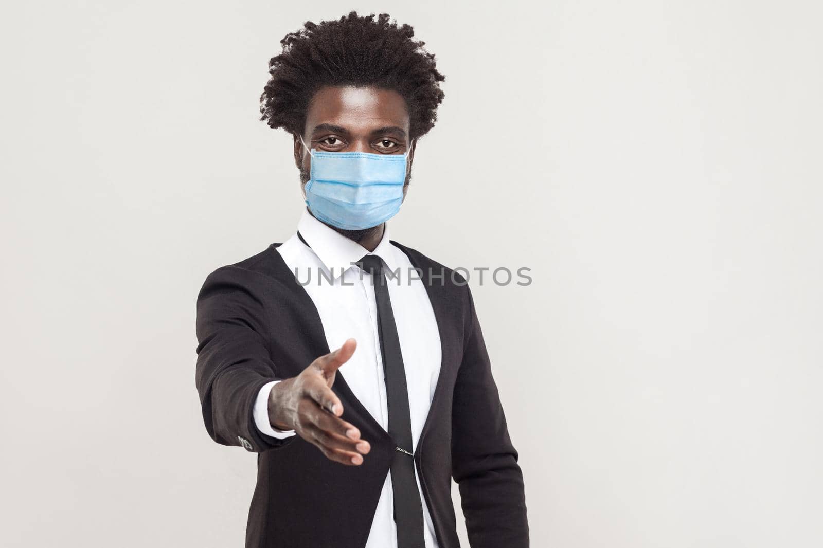 man in black suit with surgical medical mask standing and giving hand for help, support or greeting. by Khosro1