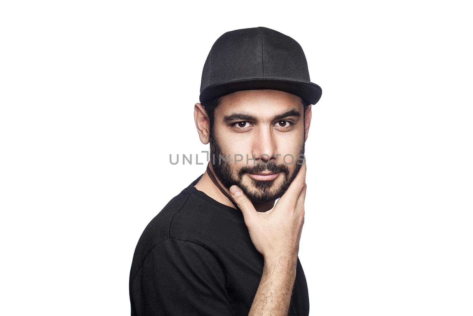 Portrait of young beautiful sexy man with black t-shirt and cap posing and looking at camera. studio shot, isolated on white background.