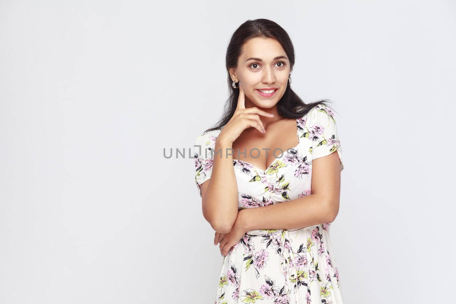 Happiness hispanic woman looking up, touching finger her chin and toothy smile. Studio shot, isolated on gray background