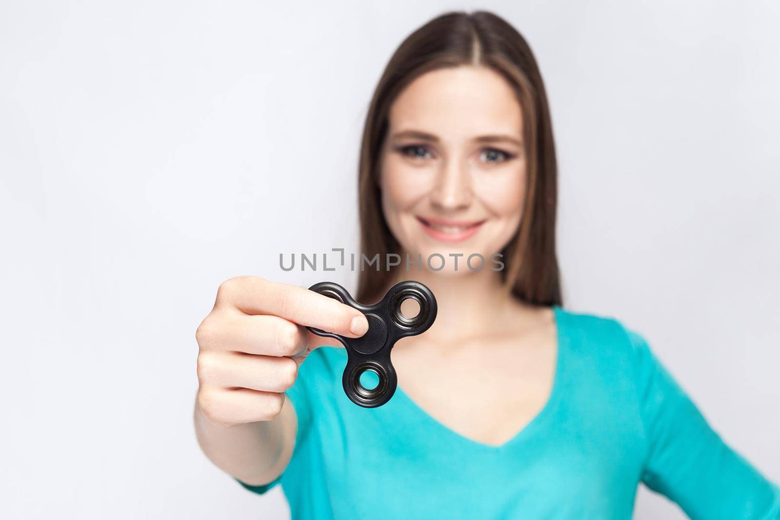 Young beautiful girl holding and playing with fidget spinner. studio shot on white background.