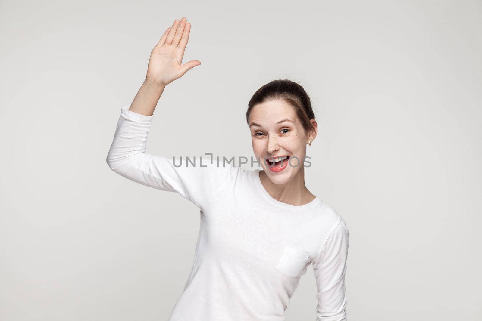 Hi! How are you? Happiness woman showing hello sign. Studio shot, gray background