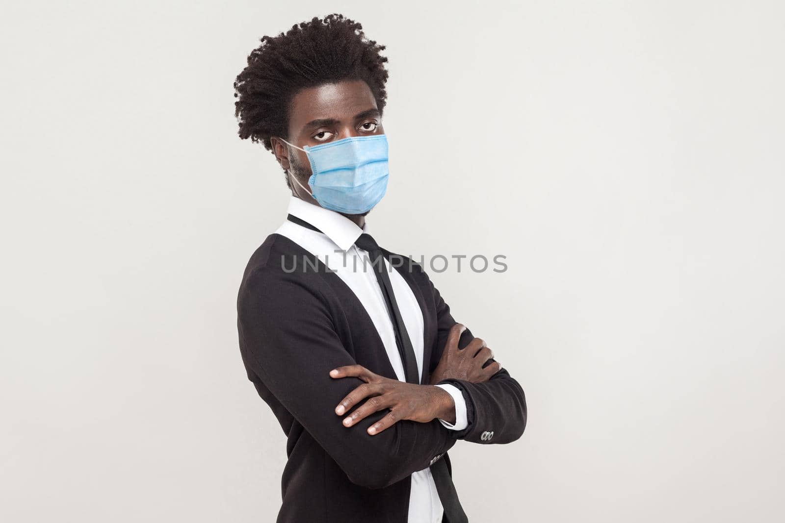 Protection against coronavirus. Alone man wearing hygienic mask to prevent infection, Covid-19. folded arms and looking at camera with sad worry face. indoor studio shot isolated on gray background