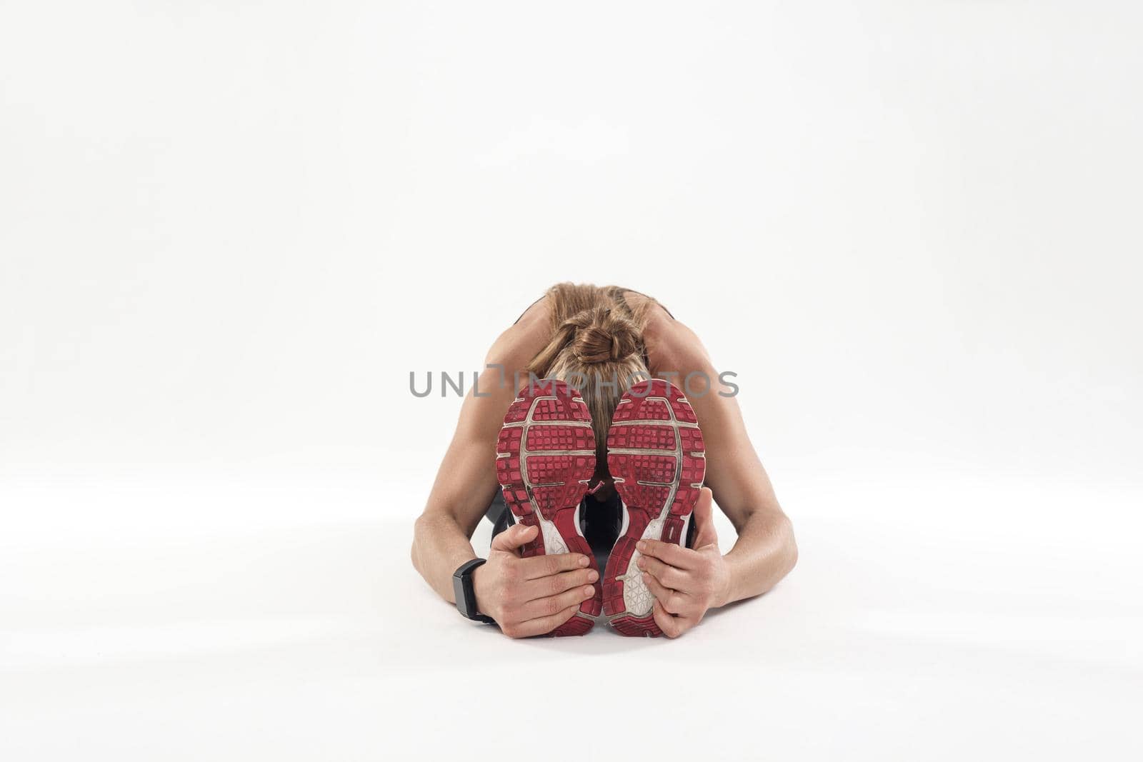 Young adult woman doing yoga, tilt forward. Studio shot, gray background