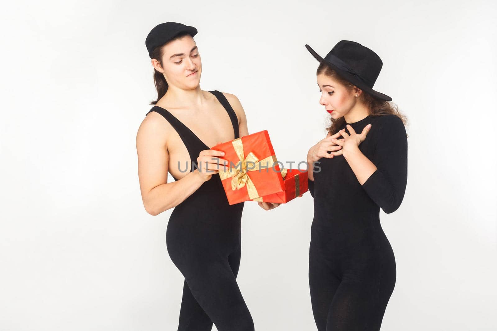 Girl receives a birthday present from a young adult man. Studio shot, isolated on white background