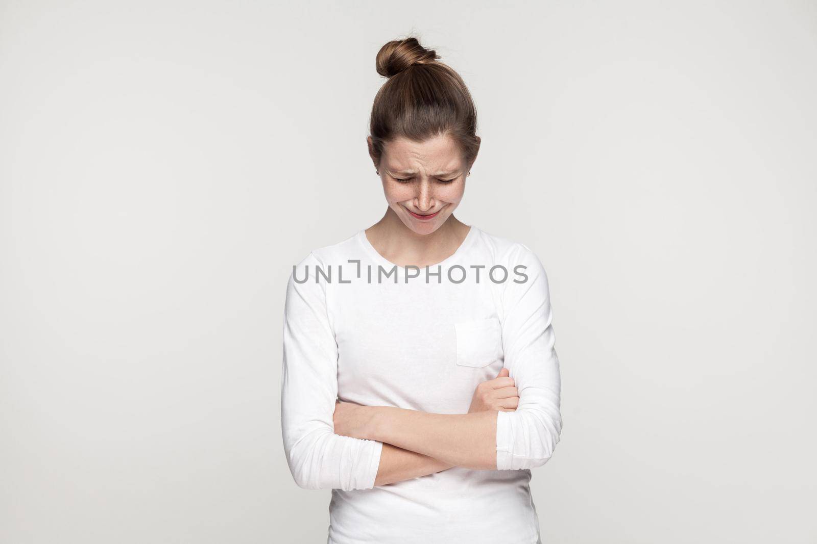 Sadness girl crossed hands and cry. Studio shot, gray background