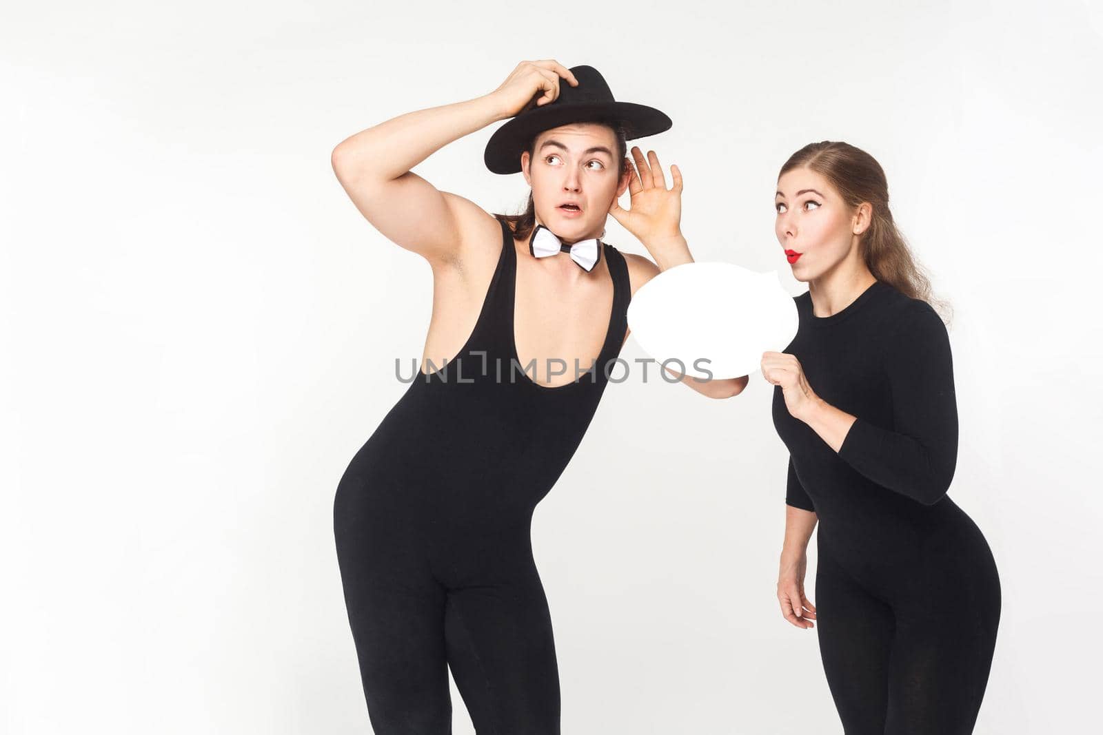 Young adult woman tells gossip in secret. Studio shot, isolated on white background