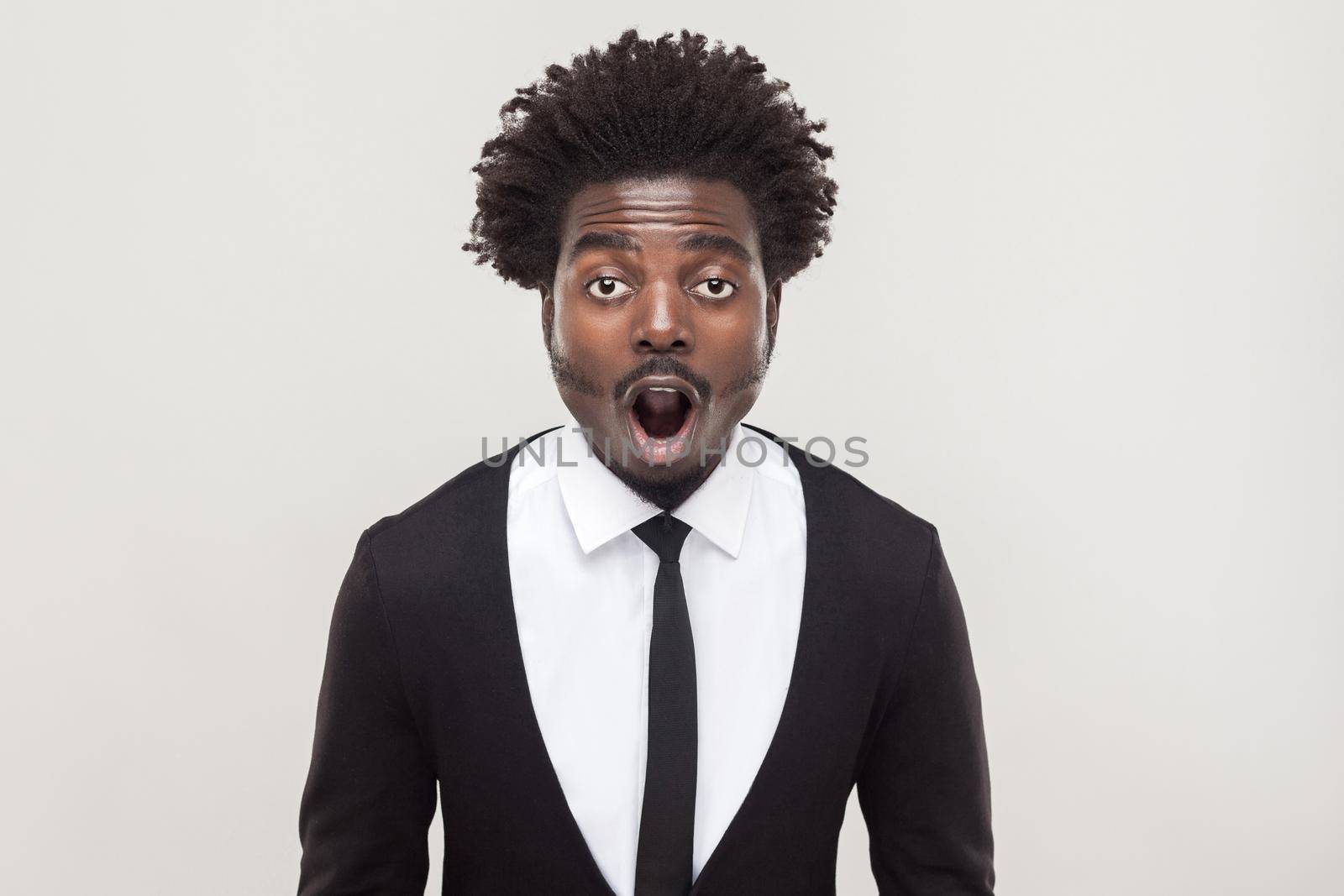 Amazement businessman looking at camera with shocked face. Studio shot, gray background