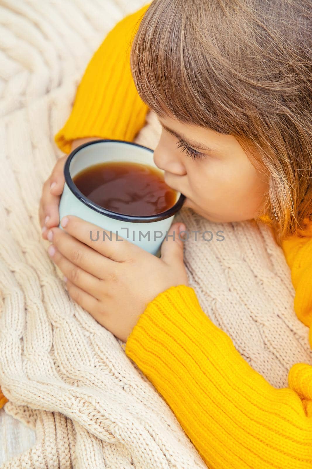 Child with a cup of tea in his hands. Selective focus. autumn.