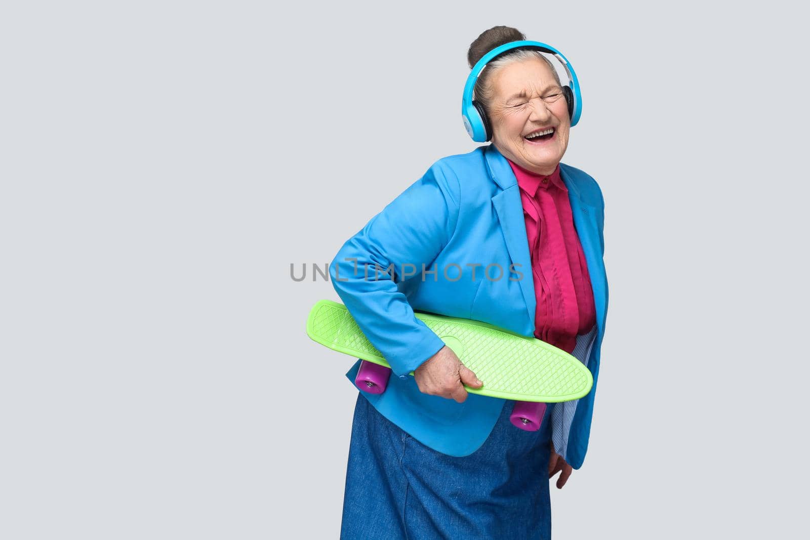 grandmother holding green skateboard listening music and laughing with closed eyes. by Khosro1