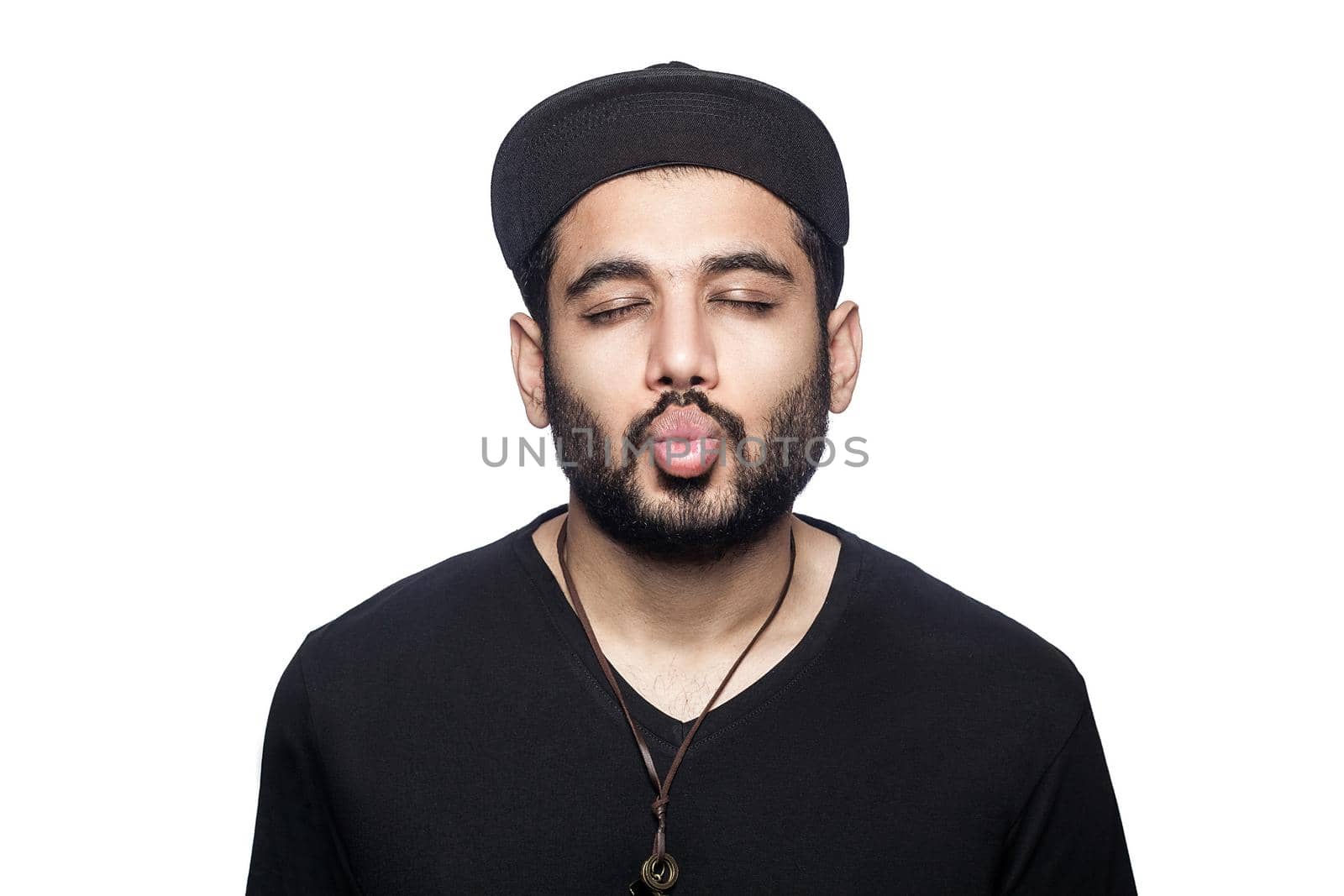 Portrait of young man with black t-shirt and cap kissing with closed eyes. studio shot, isolated on white background.