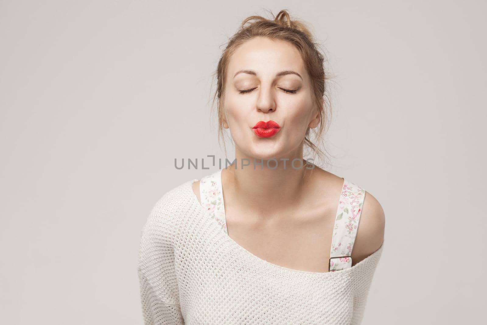 Closeup portrait of romantic woman send air kiss at camera. Studio shot, isolated on gray background