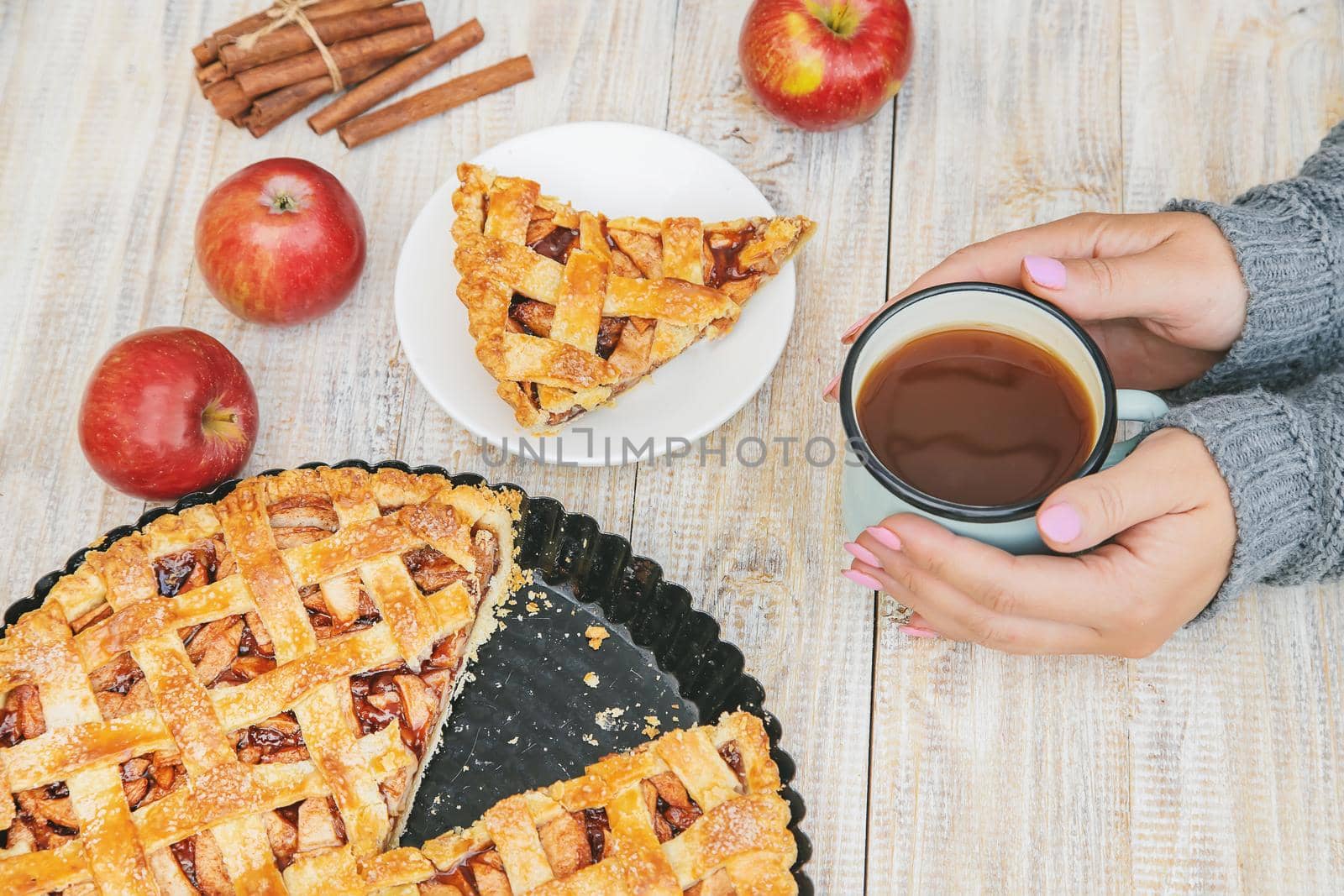Girl with a cup of tea and a pie with apples and cinnamon. Selective focus. food.