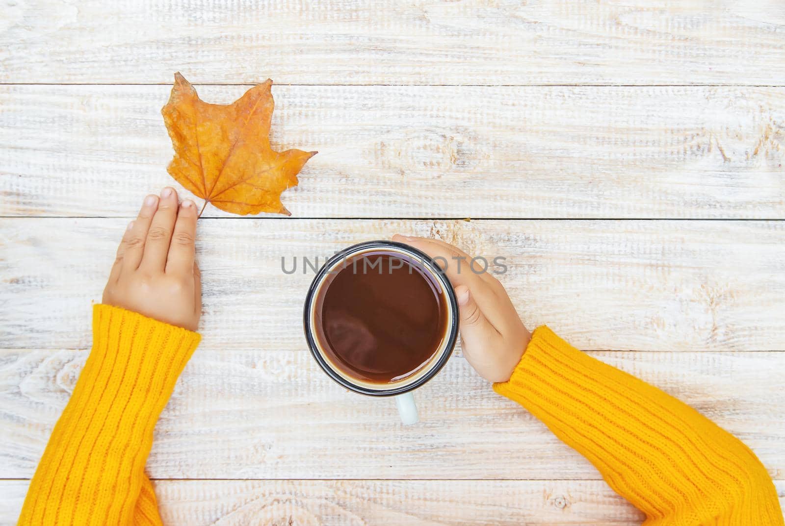 Child with a cup of tea in his hands. Selective focus. autumn.