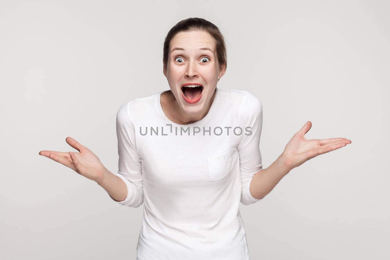 Wow. Woman open mouth and looking at camera with open mouth and big eyes. Studio shot, gray background