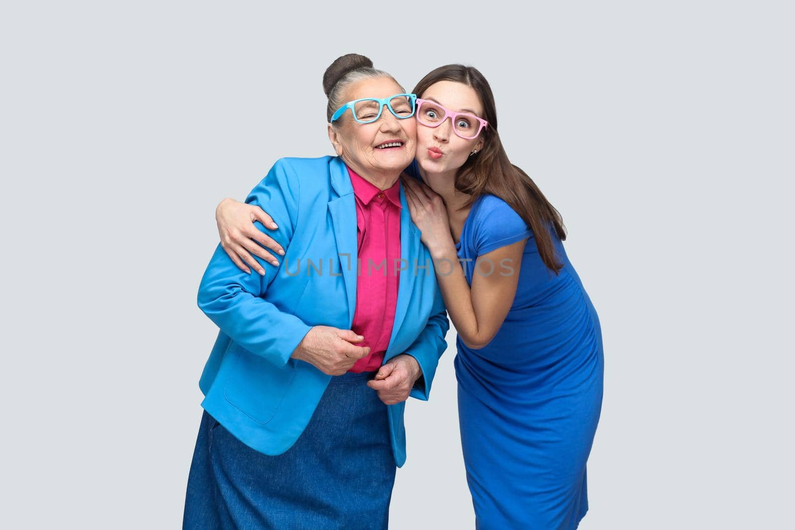 Grandmother with grandchild hugging and have fun together in family. kiss and toothy smile and good relationship. Friendship and mutual understanding. indoor, studio shot, isolated on gray background