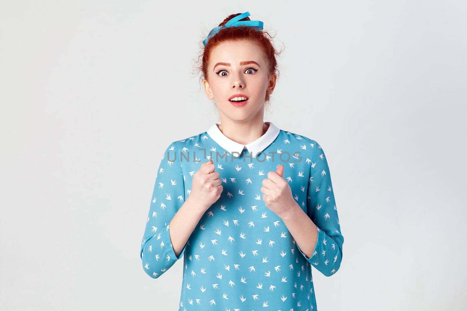 Yes! Isolated studio shot on gray background of happy successful young redhead girl winner, feeling lucky, looking at camera, excitement and joy, smiling cheerfully.