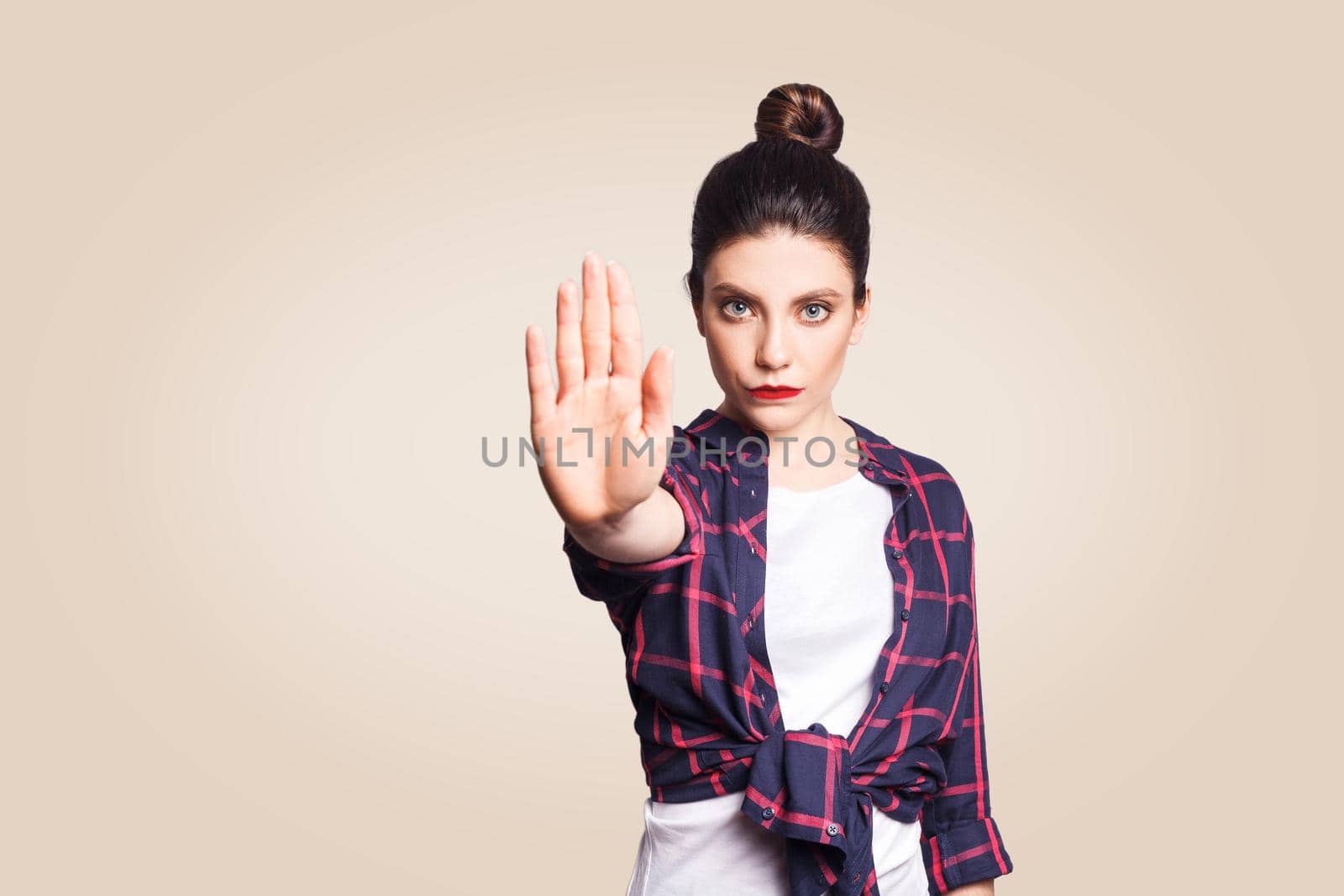 Young annoyed woman with bad attitude making stop gesture with her palm outward, saying no, expressing denial or restriction. Negative human emotions, feelings, body language. Selective focus on face.