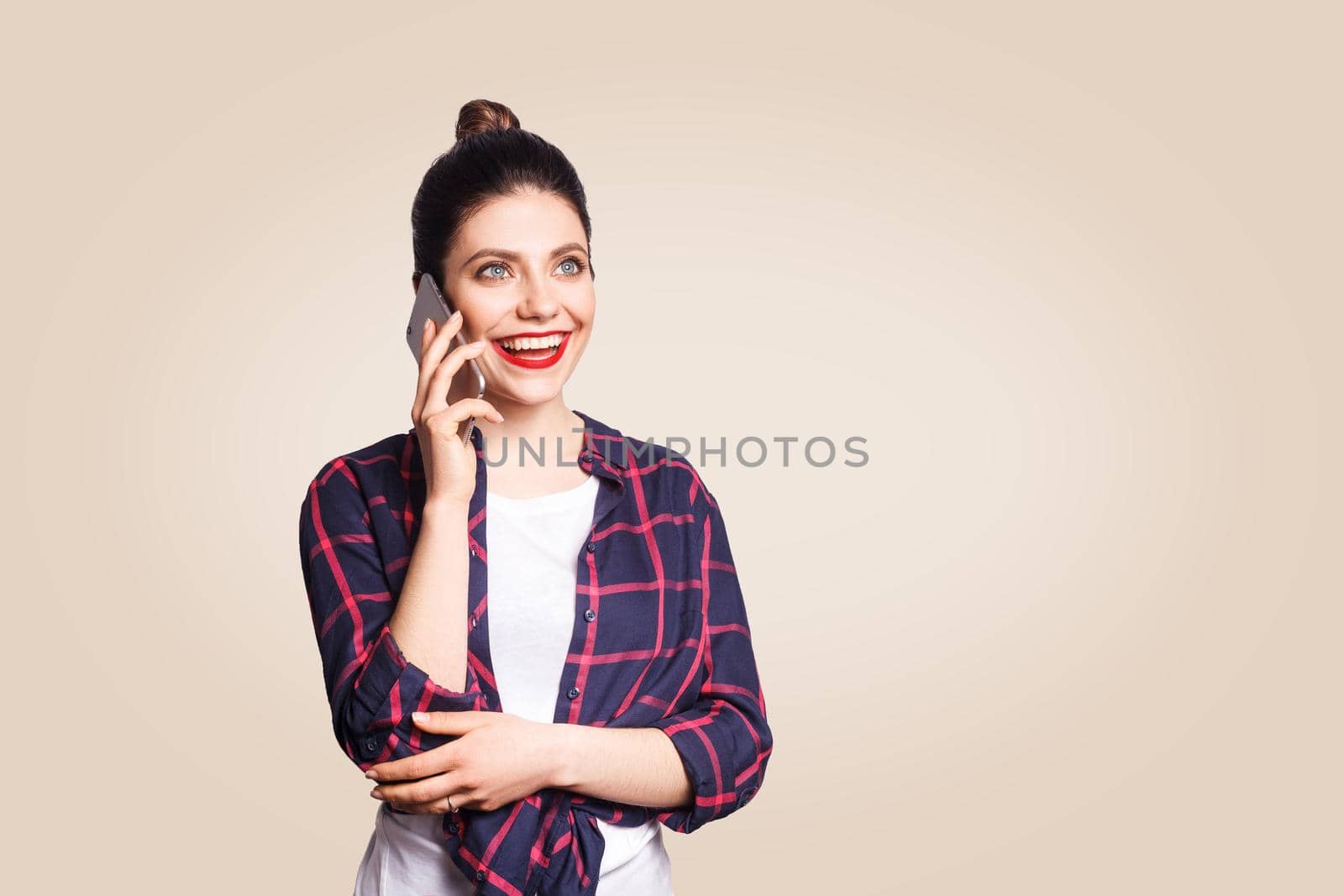 Young beautiful woman in casual style speaking with smart phone. studio shot on beige background.