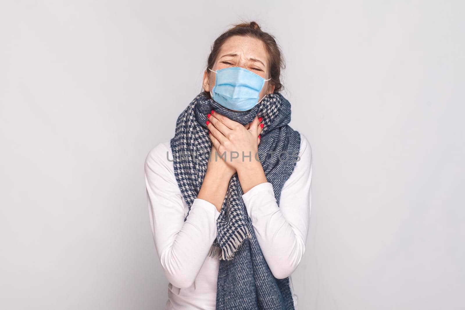 Sick young woman with surgical medical mask and blue scarf feeling bad and throat pain. by Khosro1