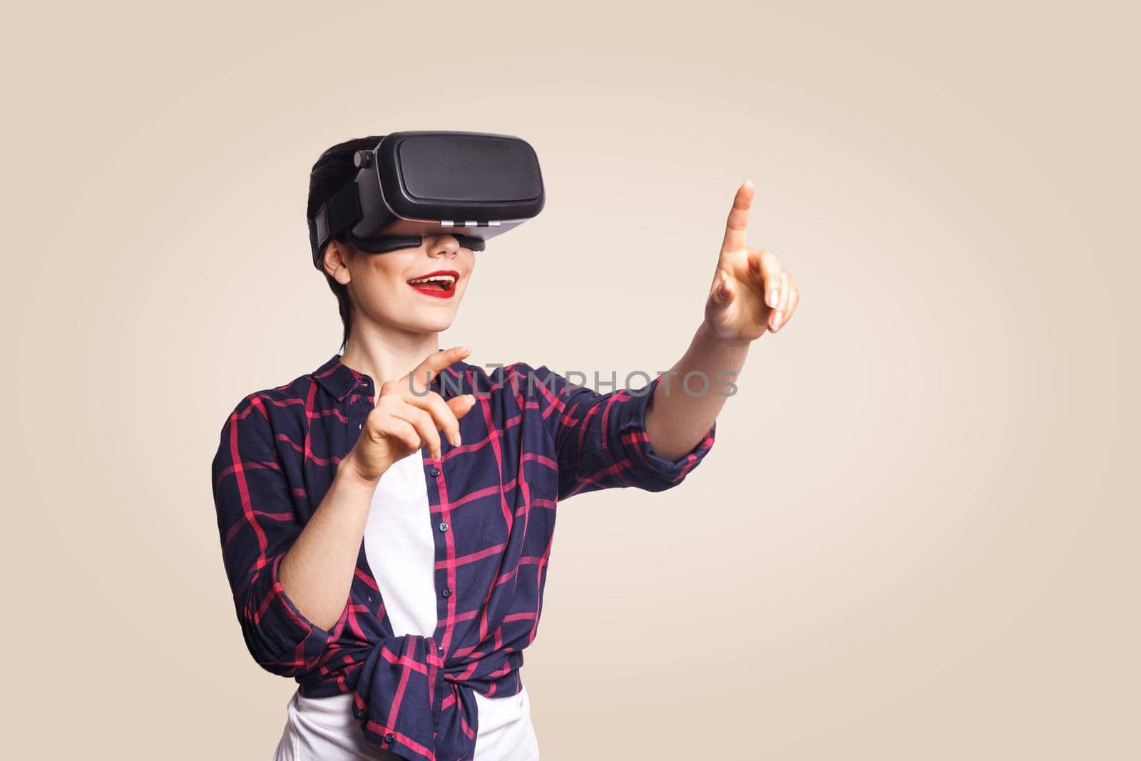 Young beautiful woman in casual style with virtual reality headset on beige background. studio shot. .