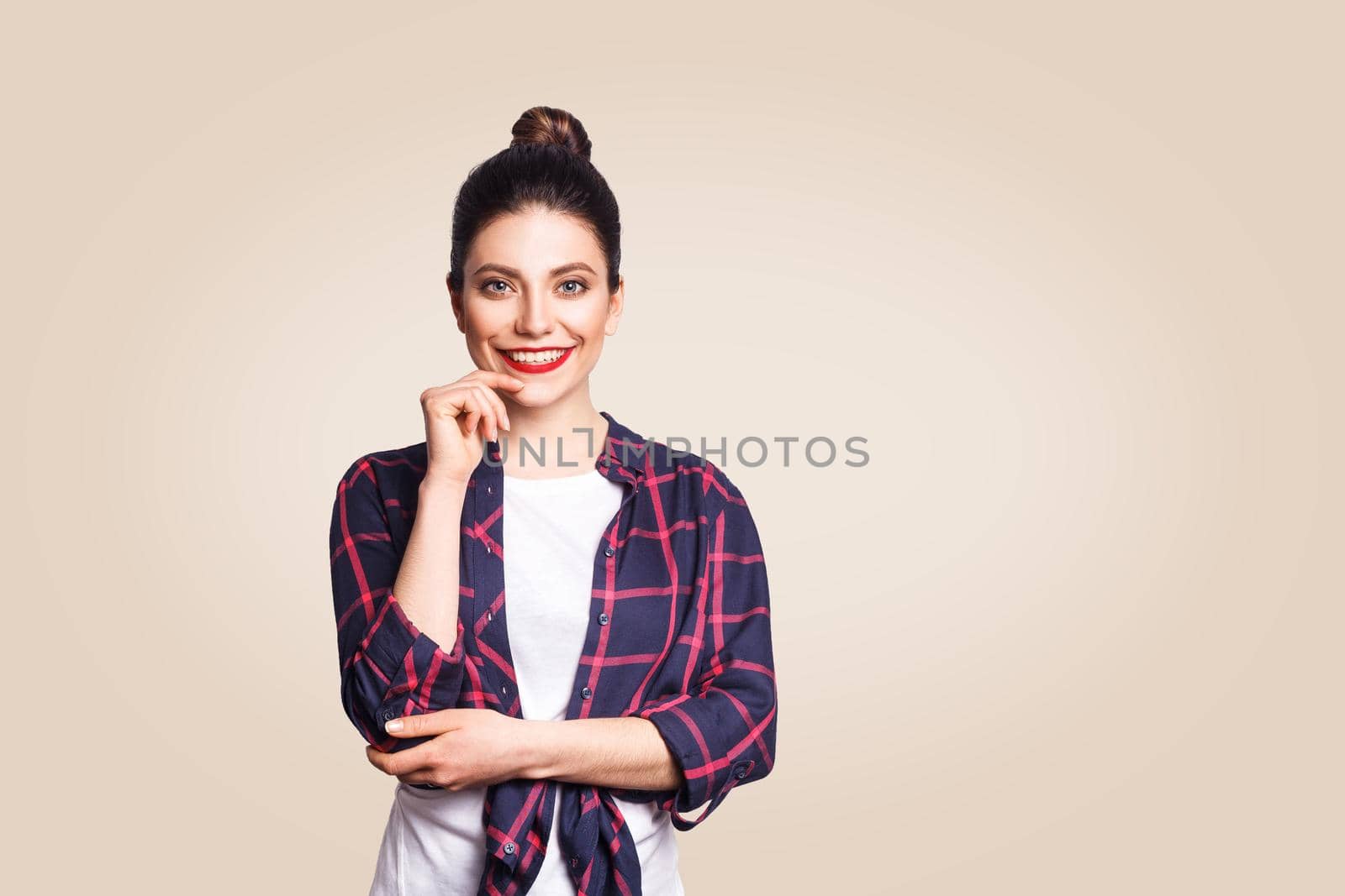 Portrait of beautiful happy girl in casual style looking at camera with toothy smile. studio shot on beige background.