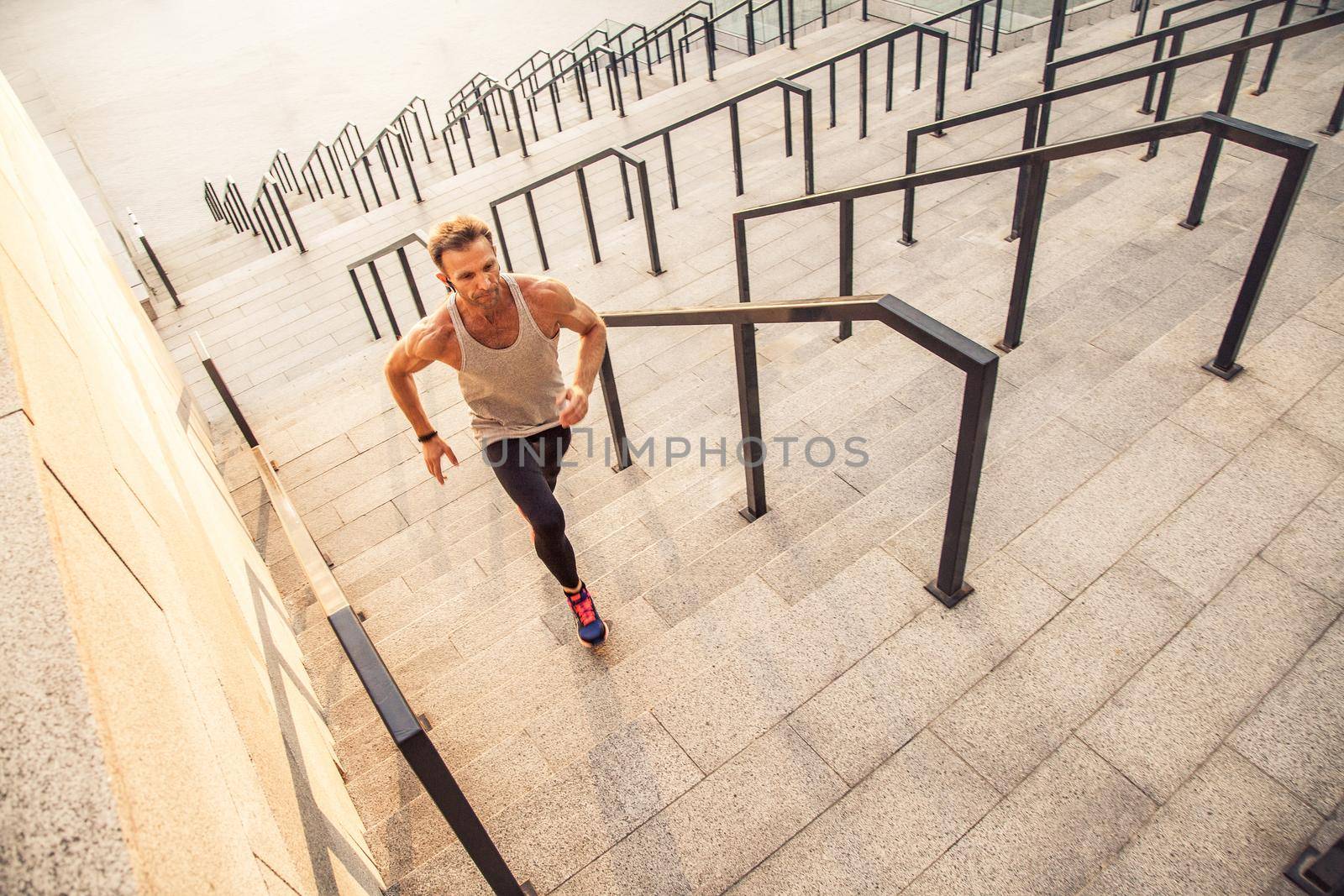 Fitness, sport, exercising and people healthy lifestyle concept. Man running upstairs in the city.