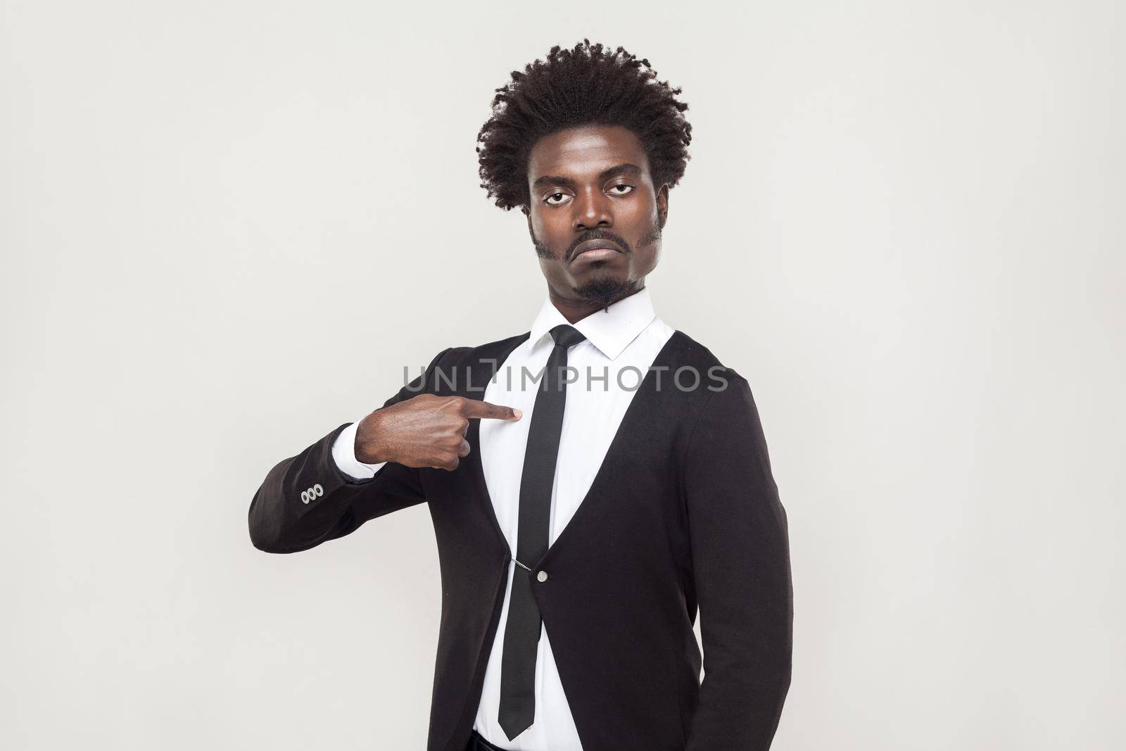 Well dressed proud man looking at camera with chesty face. Studio shot, gray background