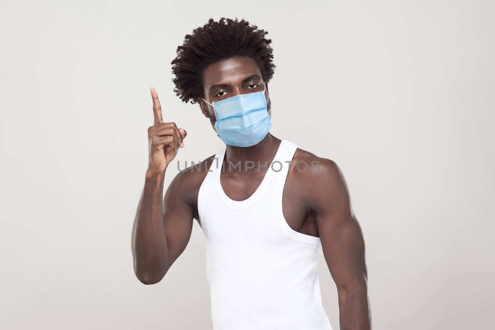 man in white shirt with surgical medical mask standing holding finger up and looking at camera. by Khosro1