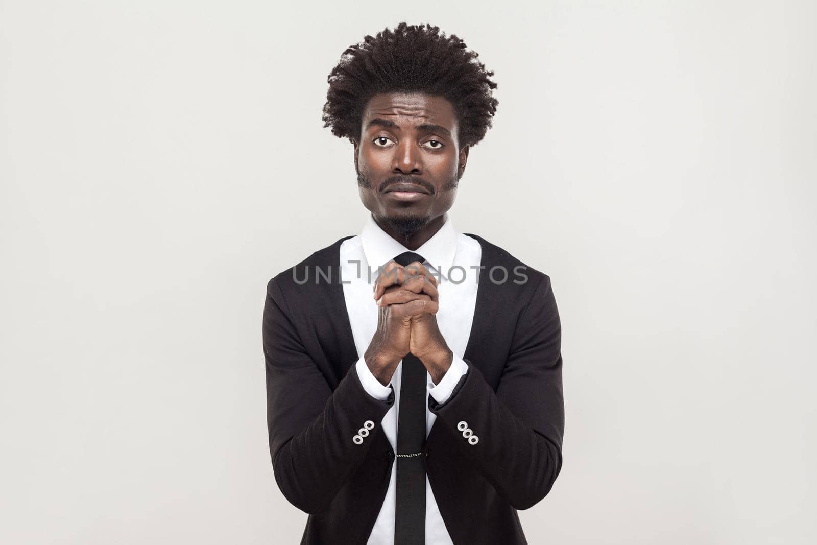 Sorry, hope concept. African businessman looking at camera and apologize. Studio shot, gray background