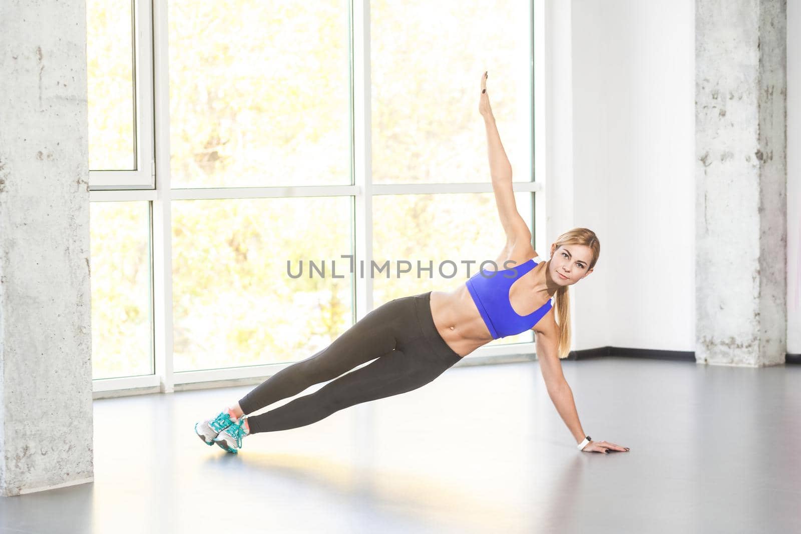 Yoga pose. Vasisthasana exercise. Blonde woman balancing on one hand. Studio shot