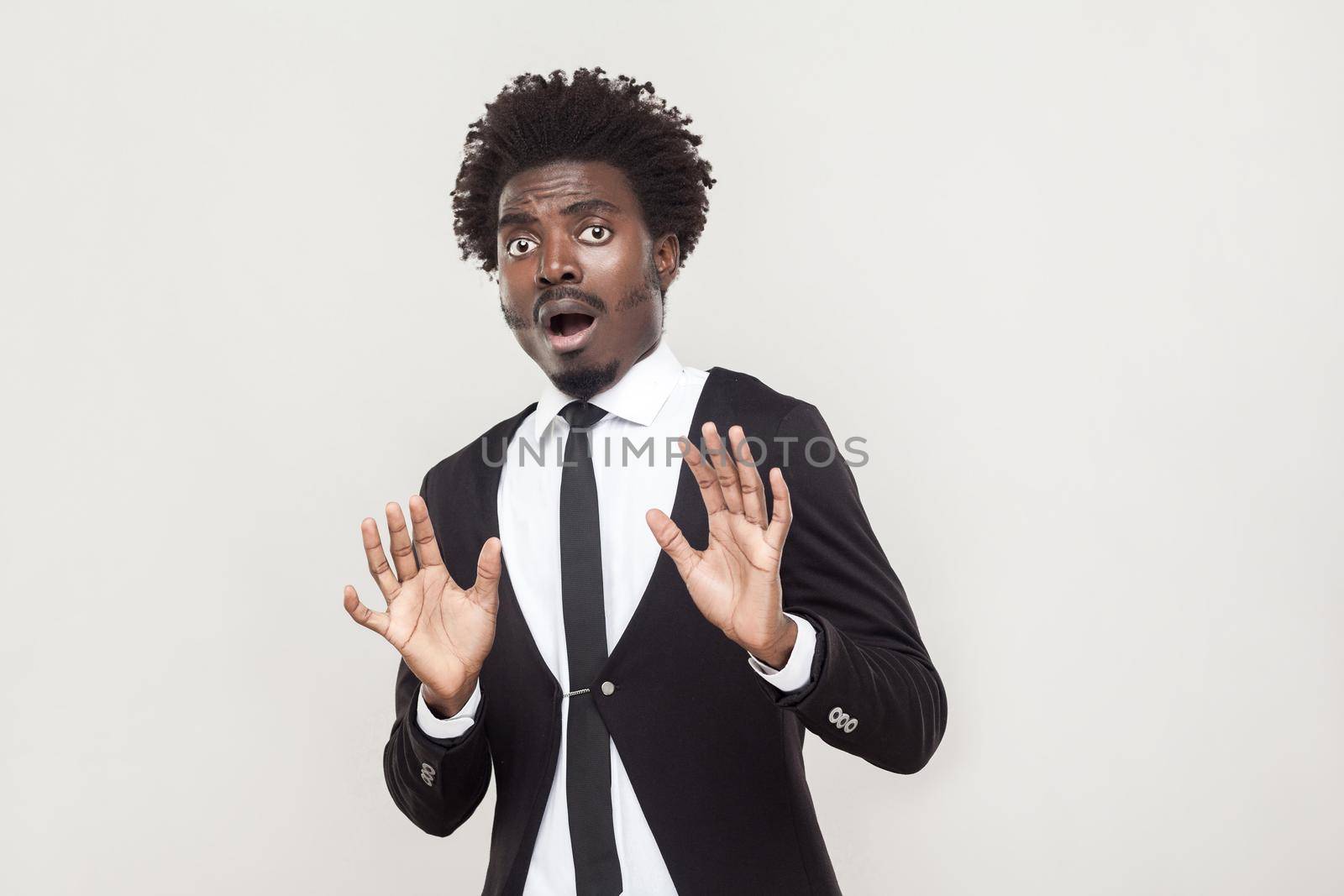 Well dressed man looking at camera with shocked face. Studio shot, gray background