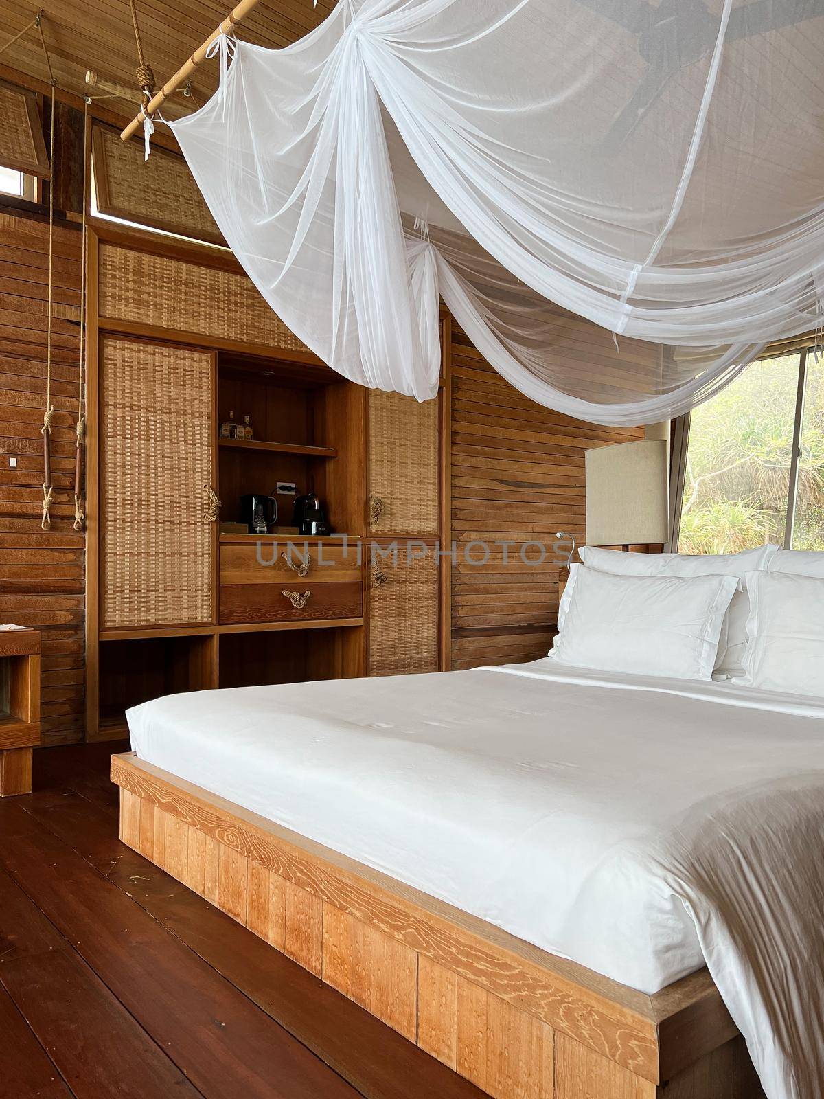 interior wooden tropical resort with bed, bedding and lighting decor on hill in tropical rainforest