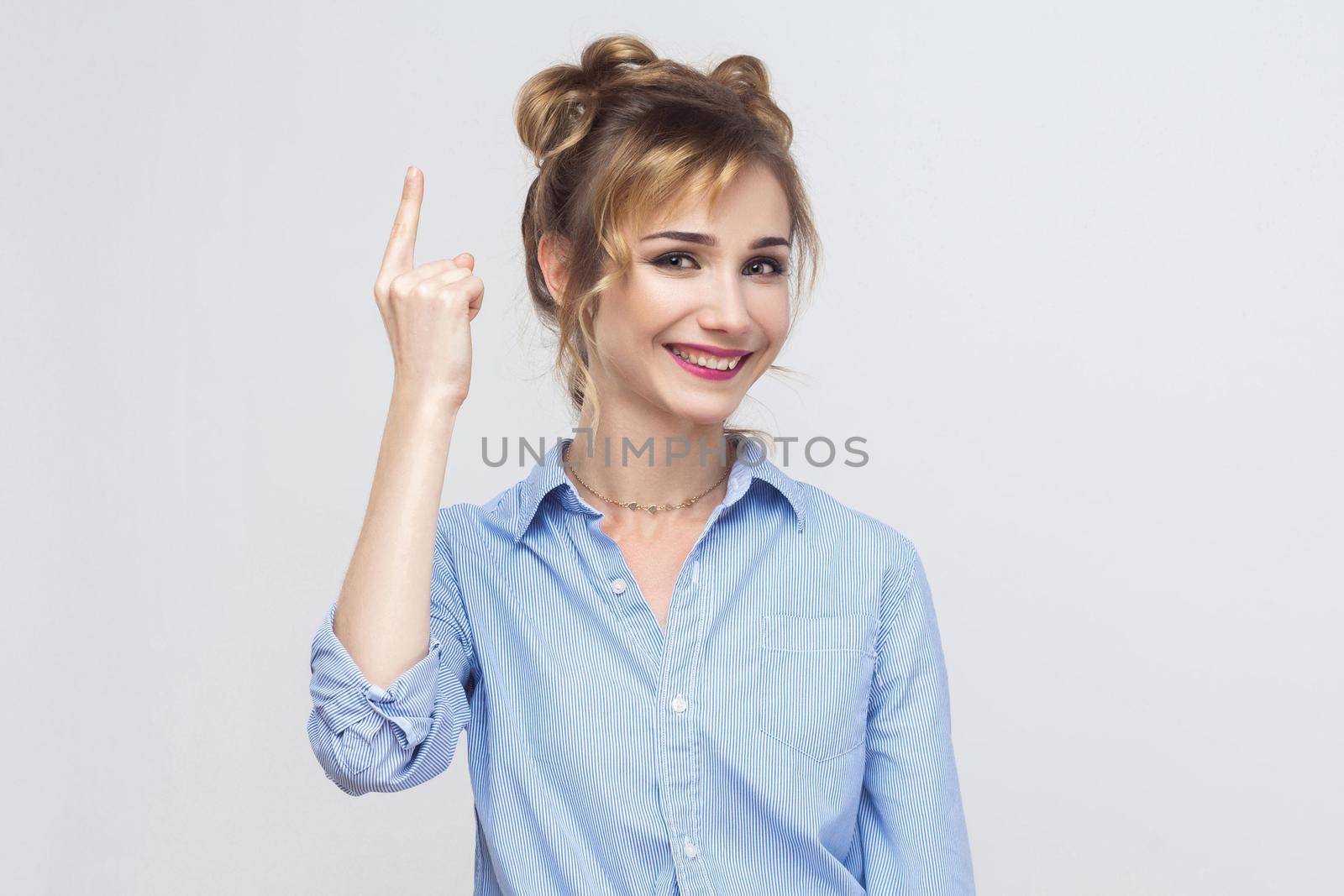 The beautiful blonde girl got the idea and she raised her finger up. Isolated studio shot on gray background