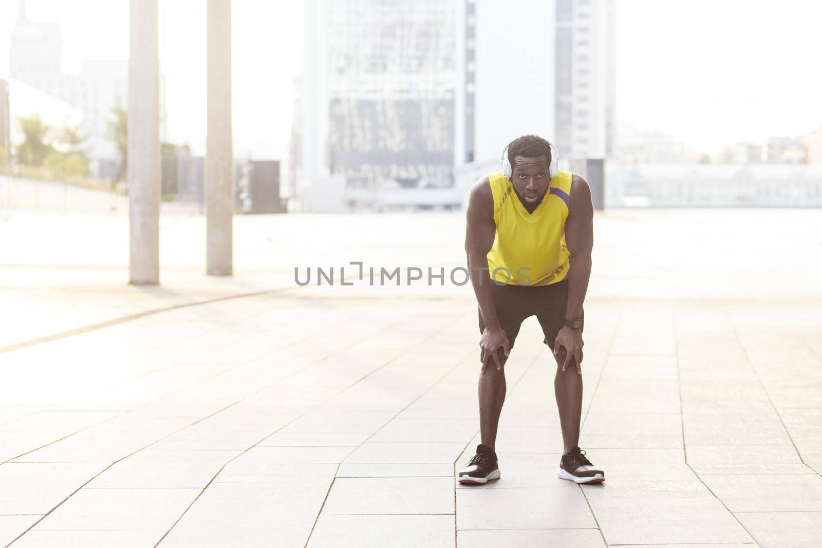 Finally finish. Sporty african man resting after workout exercise. Outdoor photo, blurred background