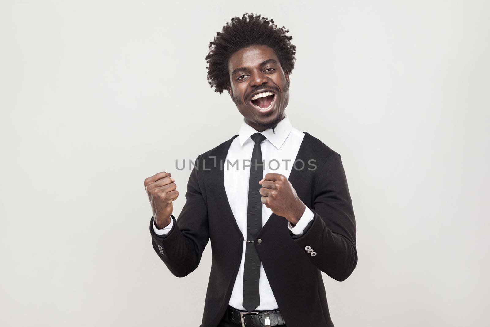 Optimistic african man rejoicing new contract. Studio shot, gray background