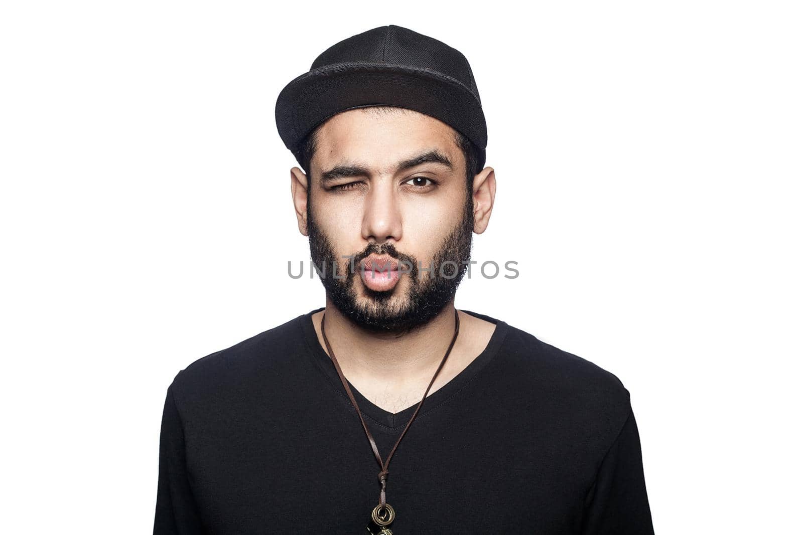 Portrait of young man with black t-shirt and cap looking at camera with wink and kiss. studio shot, isolated on white background.