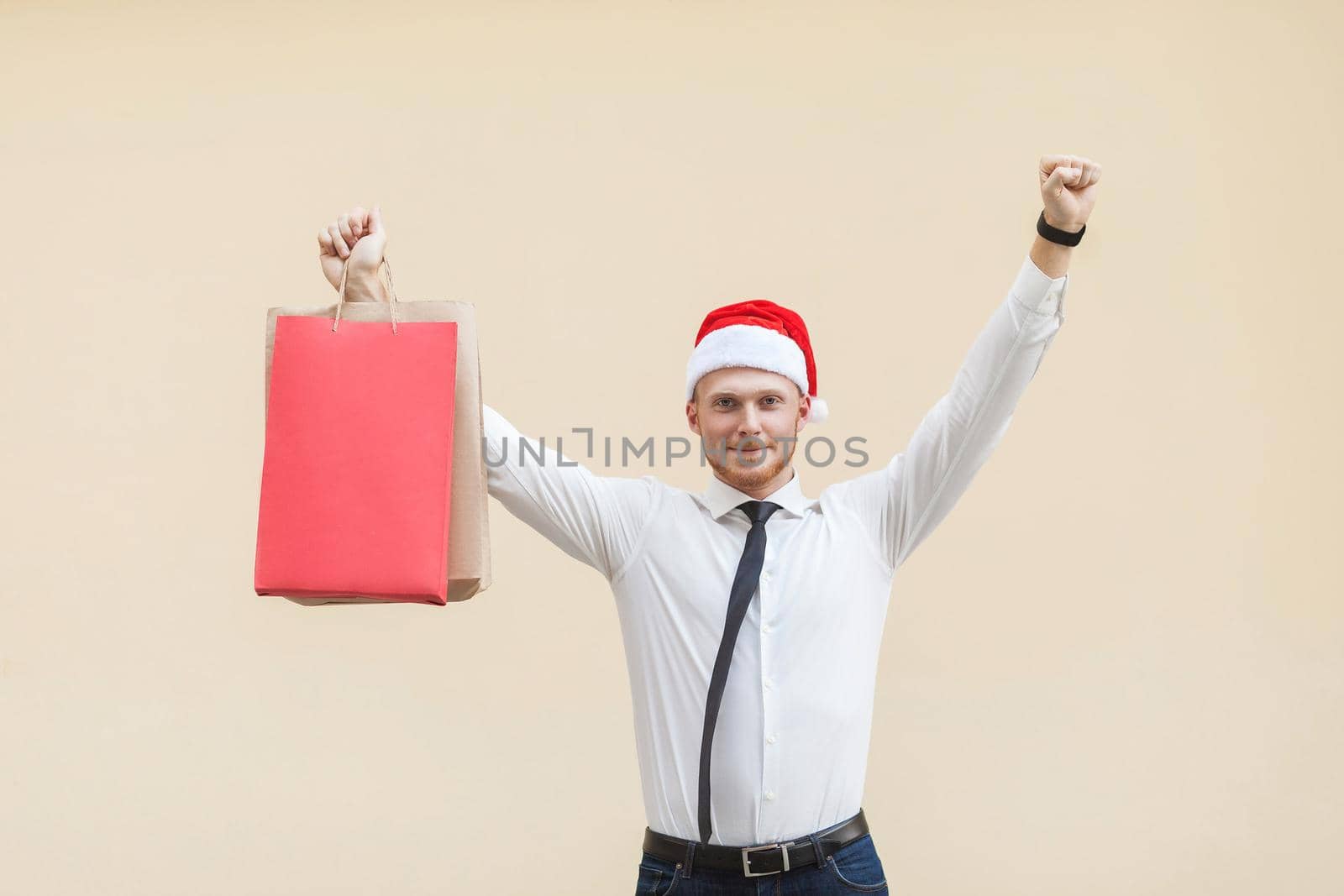 Celebrate triumph. Buy for best price in winter. Young adult ginger man looking at camera. Indoor, studio shot. Isolated on light orange background