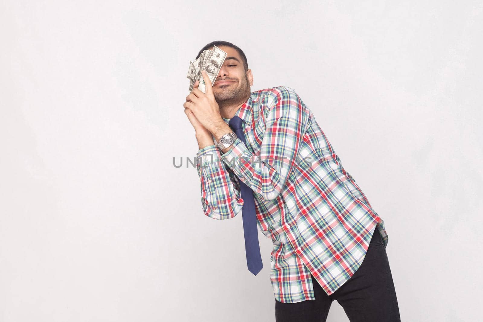 businessman in checkered shirt with blue tie standing and lean against to cheek fan of money. by Khosro1