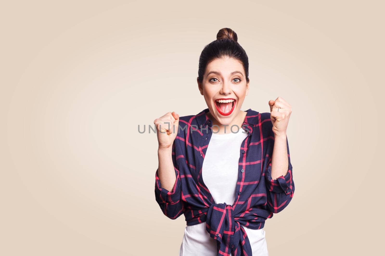 surprised portrait of happy winner ecstatic young woman with casual style having shocked look, exclaiming, keeping mouth wide open and fists clenched while celebrating success.