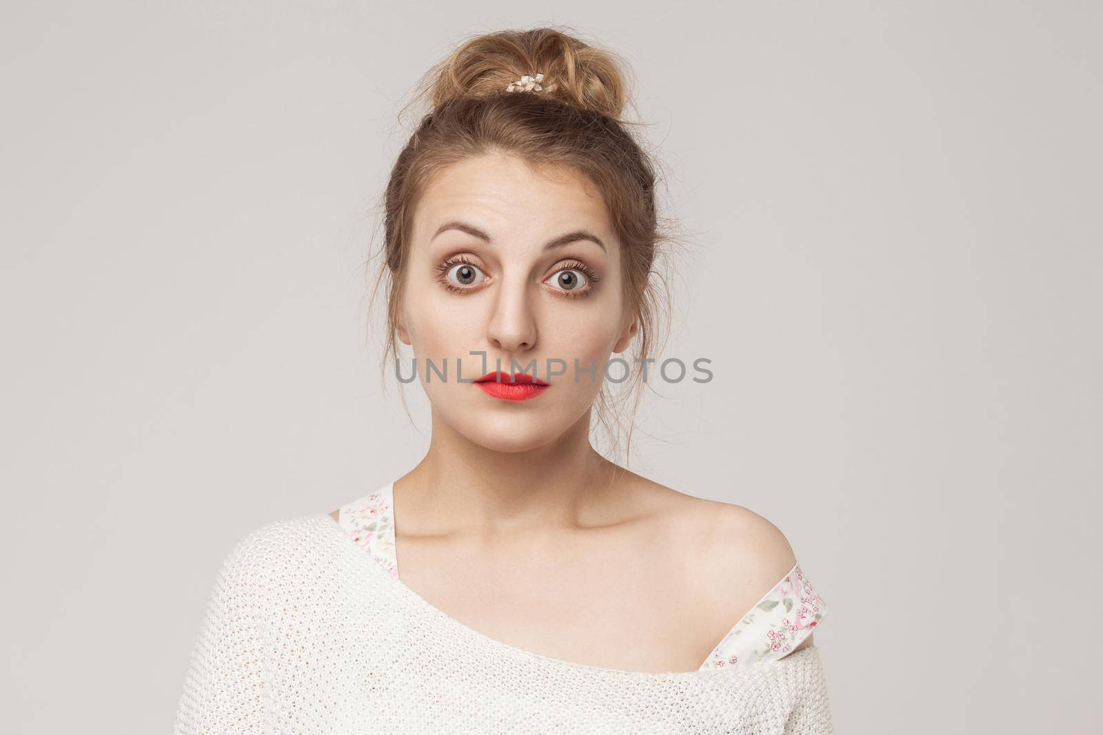 Portrait of blonde adult woman with surprised face. Studio shot, gray background