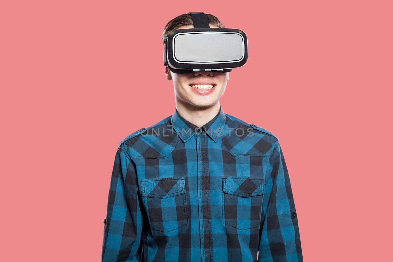 Portrait of young man with virtual reality headset. indoor, isolated on pink background.