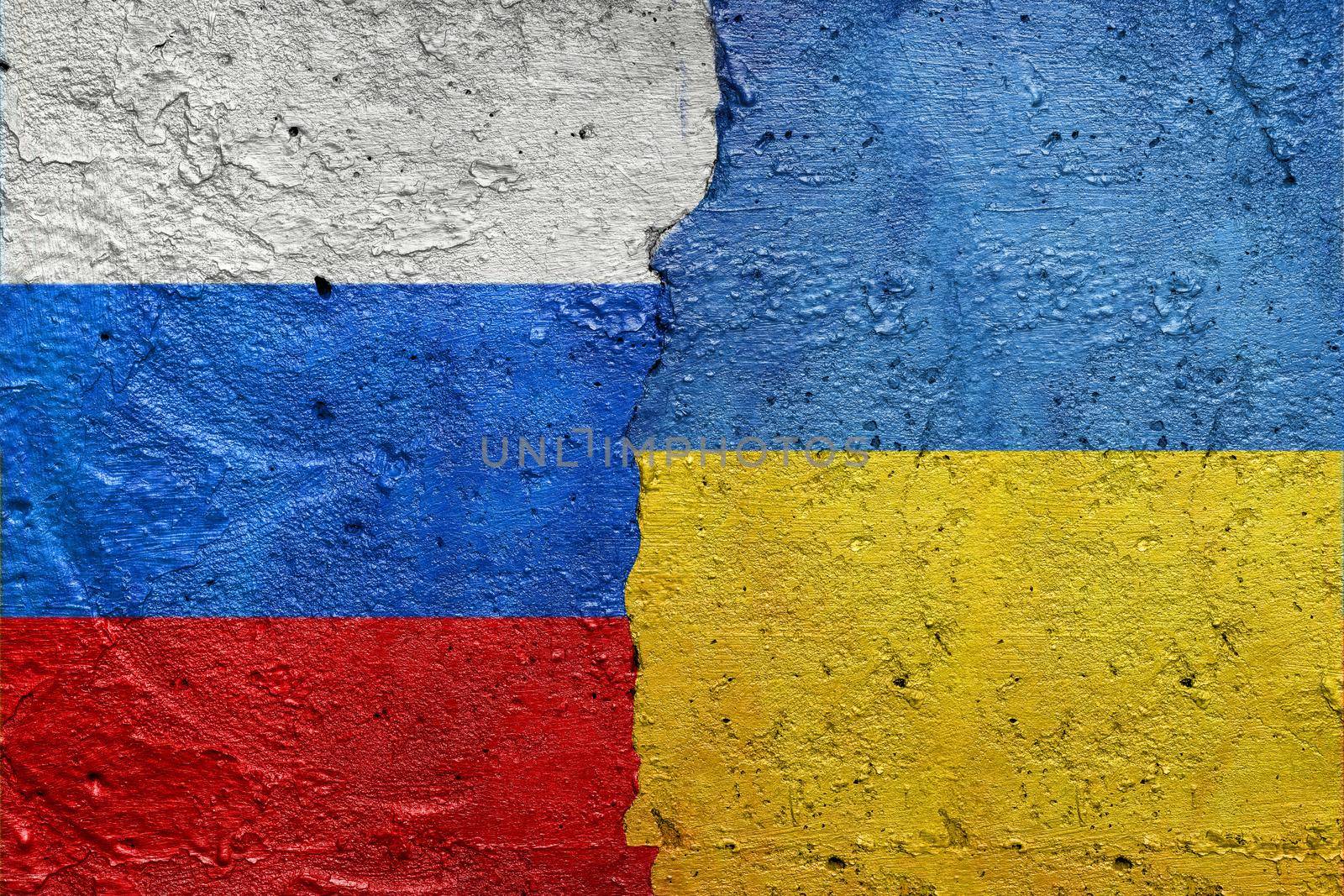 Russia vs Ukraine - Cracked concrete wall painted with a Ukrainian flag on the left and a Russian flag on the right