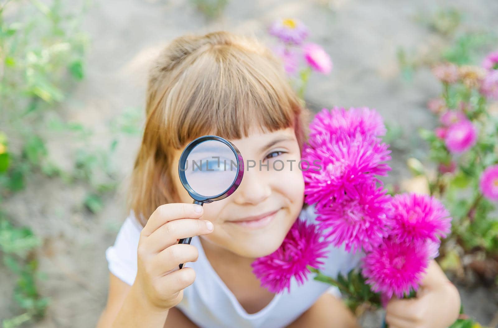Child with a magnifying glass in his hands. Selective focus. by yanadjana