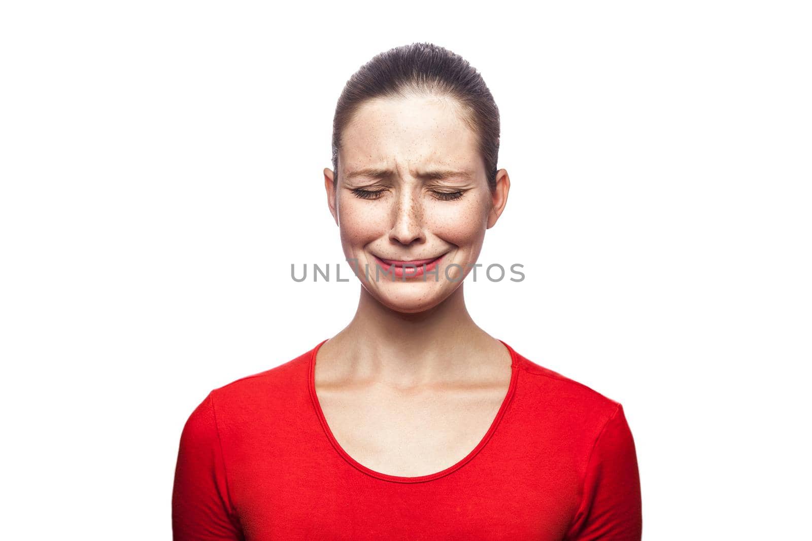 Portrait of sad unhappy crying woman in red t-shirt with freckles. closed eyes, studio shot. isolated on white background.