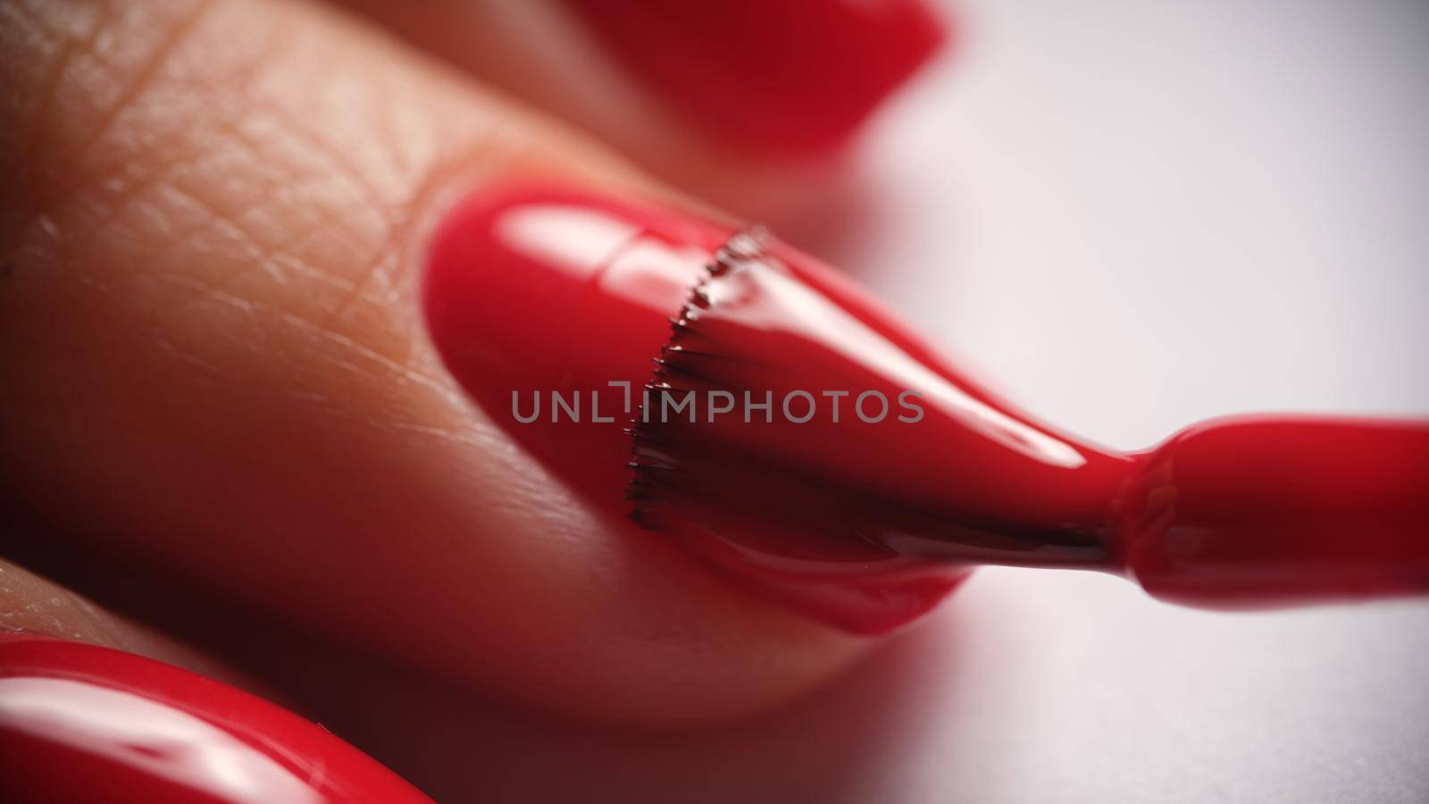 Manicurists apply red nail gel polish on finger. Manicure services and beautiful nails concept