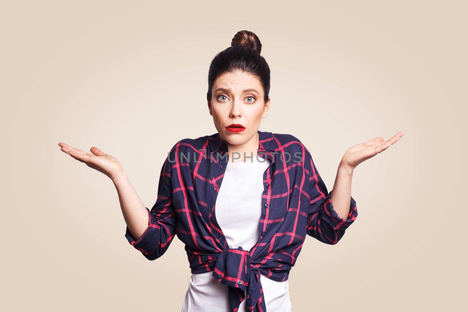 Portrait of young shocked brunette woman with casual style looking desperate or panic, keeping mouth open and making helpless gesture with her hands, doesn't know what to do.