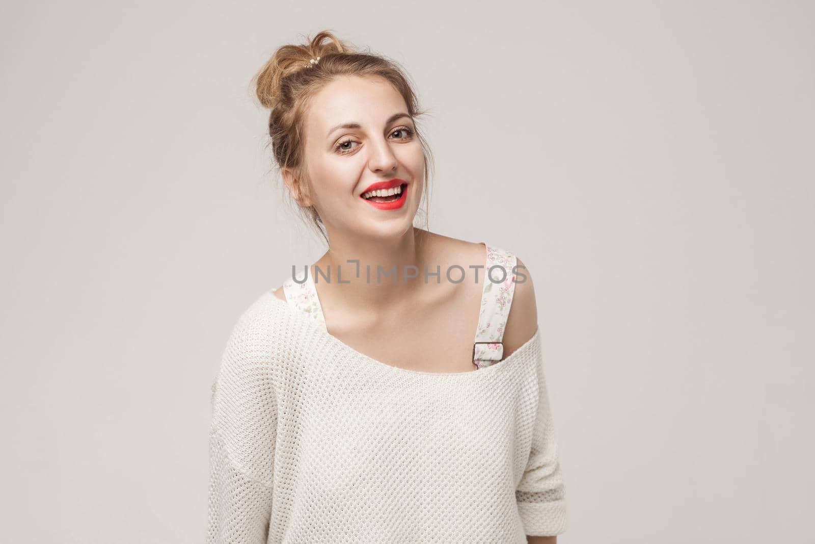 Laughing woman looking at camera and toothy smile. Studio shot, gray background