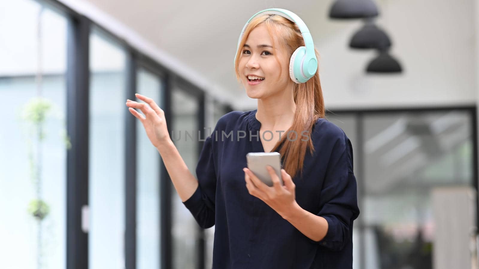 Pretty asian woman wearing headphones enjoy favorite song while spending free time at home. Mood, hobby, modern wireless technology concept by prathanchorruangsak