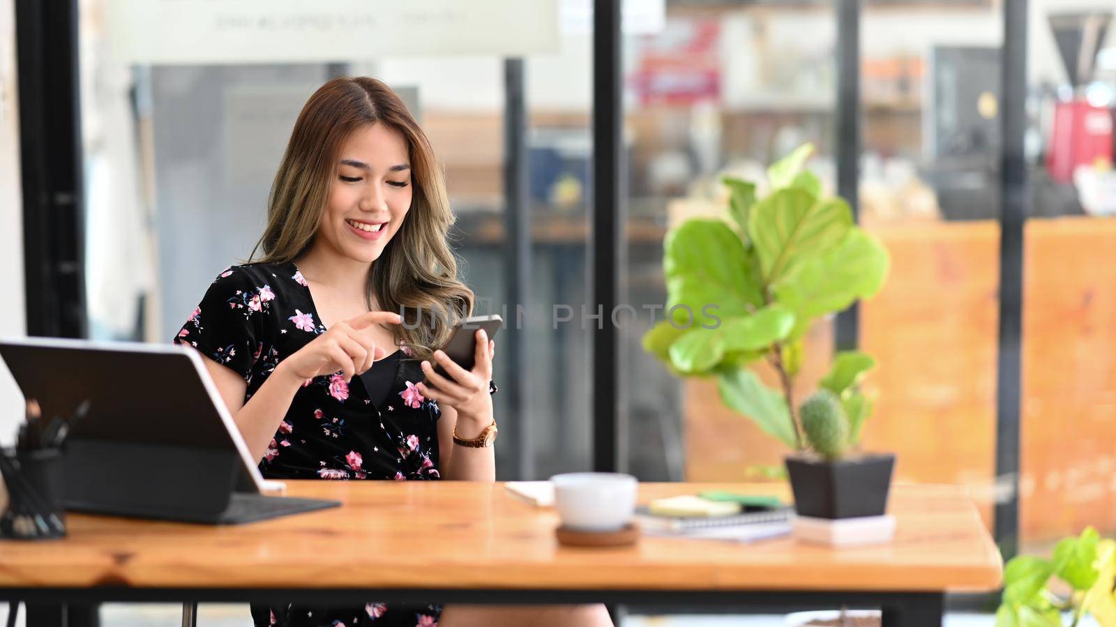 Smiling female freelancer working with computer tablet and using smart phone.